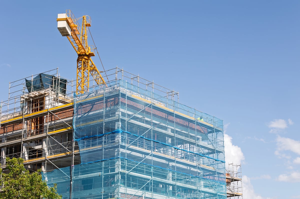 Construction crane building a modern commercial edifice with scaffolding