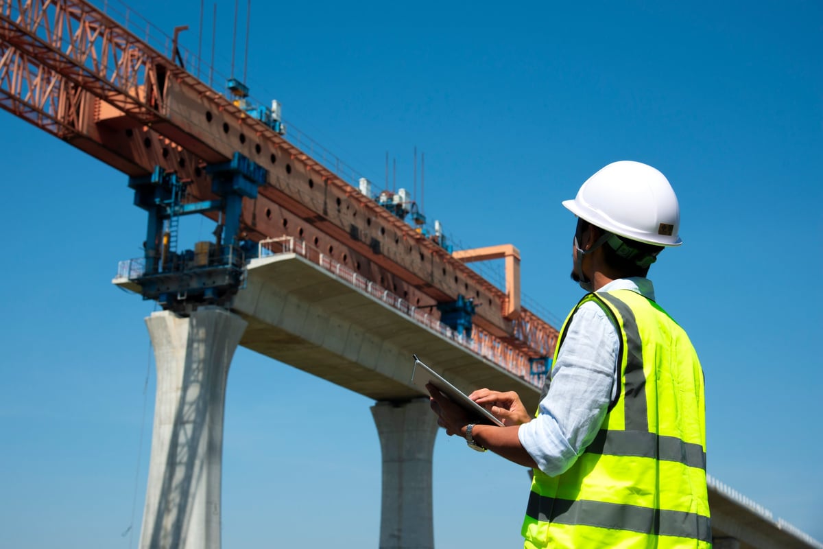 Surveyors and civil engineers using a total station with construction blueprints on a structural project