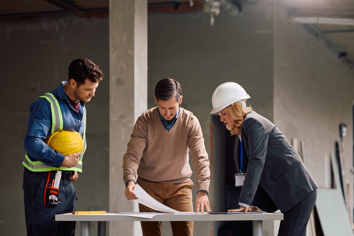 Project manager and contractor reviewing construction plans together on a design-build site