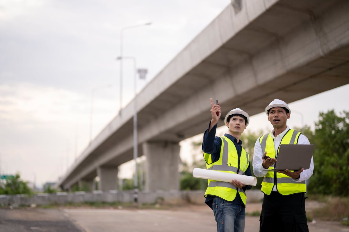 Two civil engineers in hard hats inspecting a new bridge structure