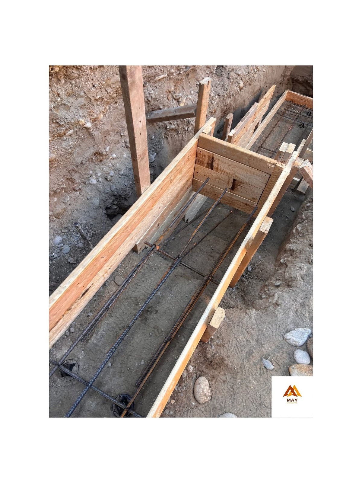Wooden construction framework with metal rebar reinforcement and electrical conduit visible in concrete foundation trench — construction management project in Scarborough Ontario — MAY Engineering Inc.