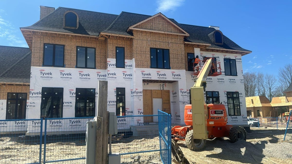 New residential house under construction with tan brick exterior covered in Tyvek wrap — permit drawings custom home project in Brampton Ontario — MAY Engineering Inc.
